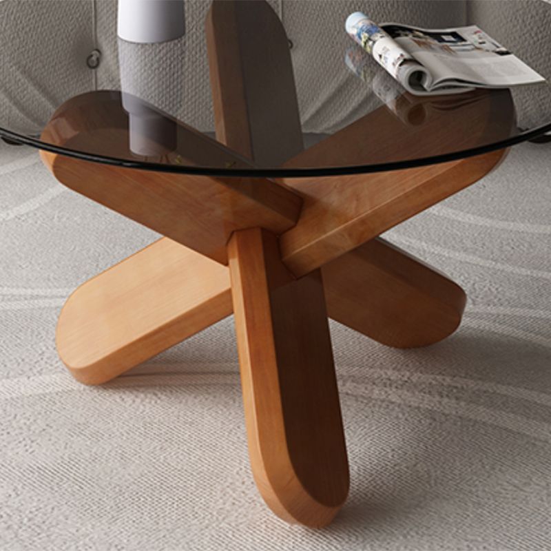 Moderner runder Couchtisch mit Glasplatte und abstraktem Holzbein