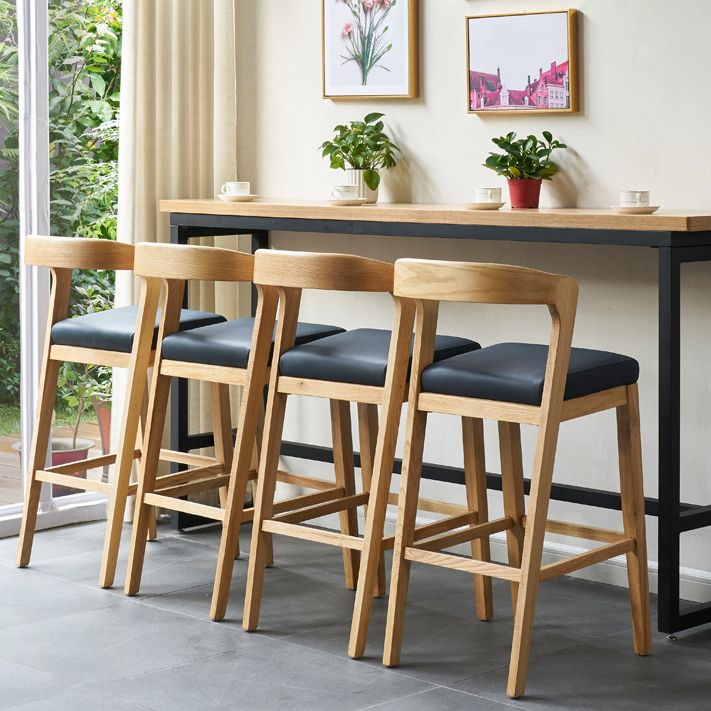 Eigentijdse houten barkruk met lage rugleuning en voetsteunkruk