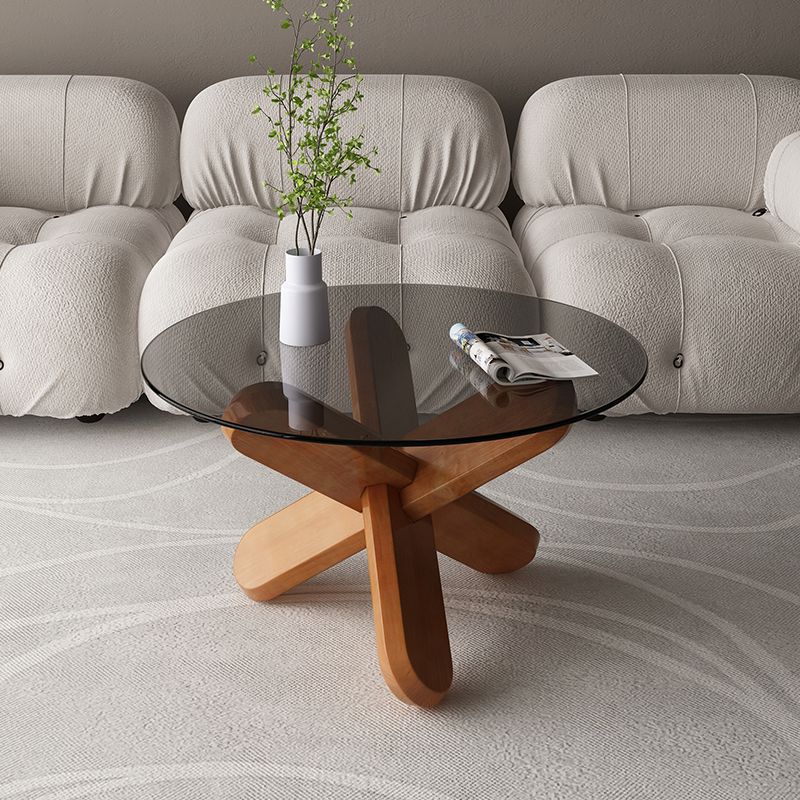 Moderner runder Couchtisch mit Glasplatte und abstraktem Holzbein