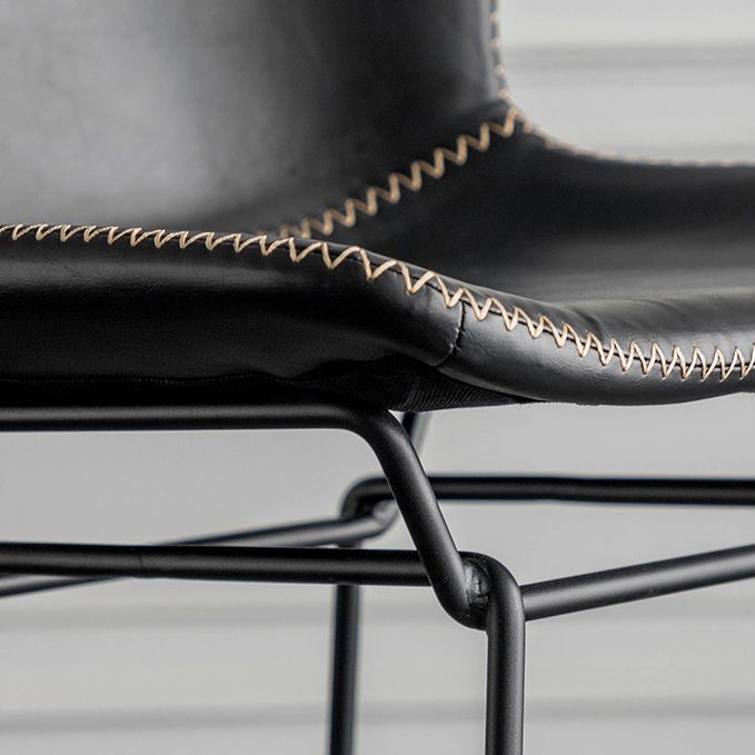 Taburete de barra de hierro industrial en la parte baja de la espalda en interiores altos con asiento de cuero falso