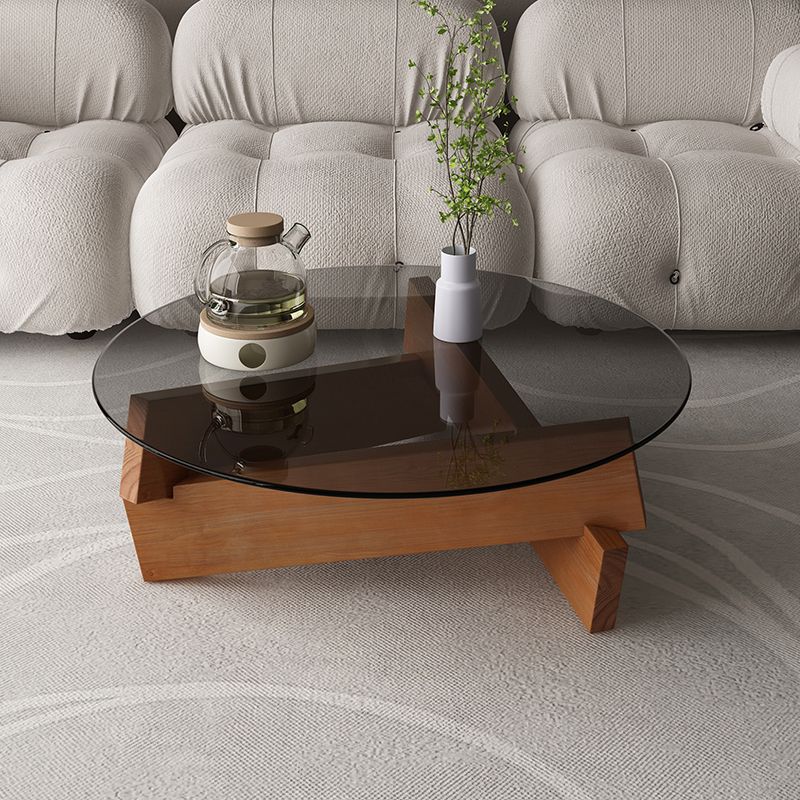 Moderner runder Couchtisch mit Glasplatte und abstraktem Holzbein