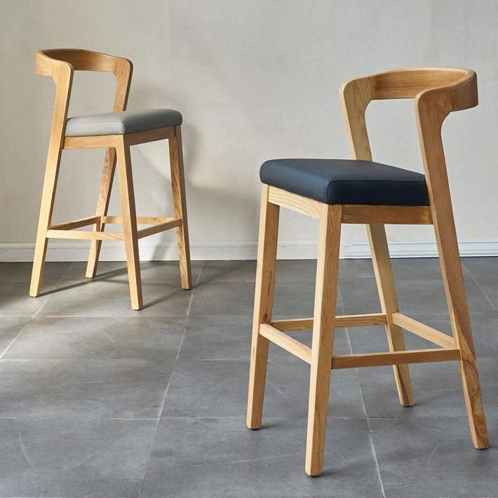 Eigentijdse houten barkruk met lage rugleuning en voetsteunkruk