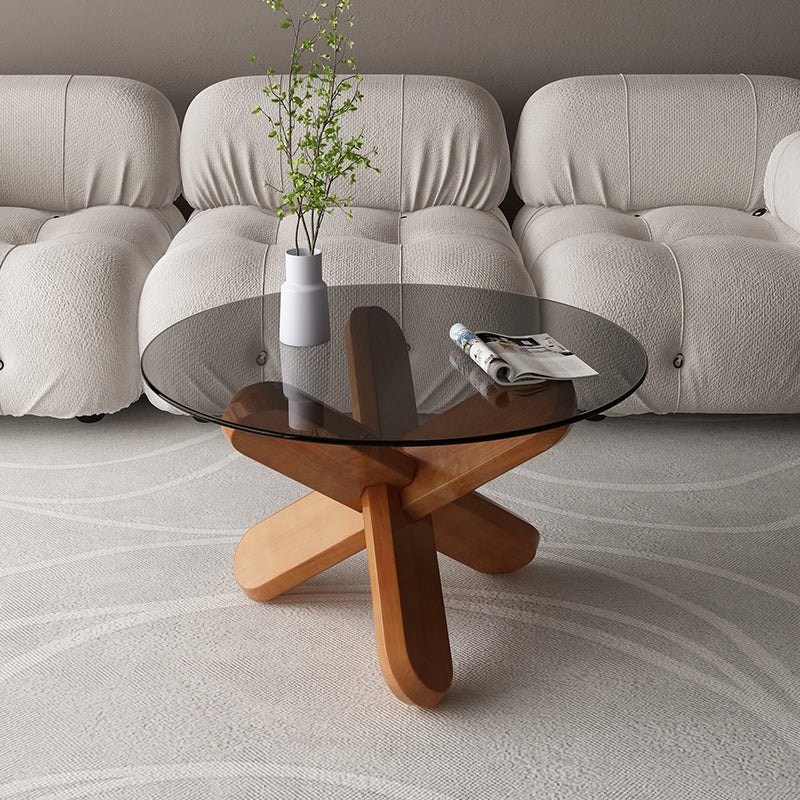 Moderner runder Couchtisch mit Glasplatte und abstraktem Holzbein