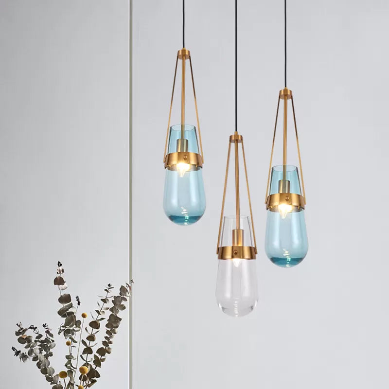 Drop Shaped Dining Room Hanging Lamp Clear/Blue Glass 1 Light Postmodern Pendulum Light with Gripper in Brass Clearhalo 'Ceiling Lights' 'Modern Pendants' 'Modern' 'Pendant Lights' 'Pendants' Lighting' 1937119