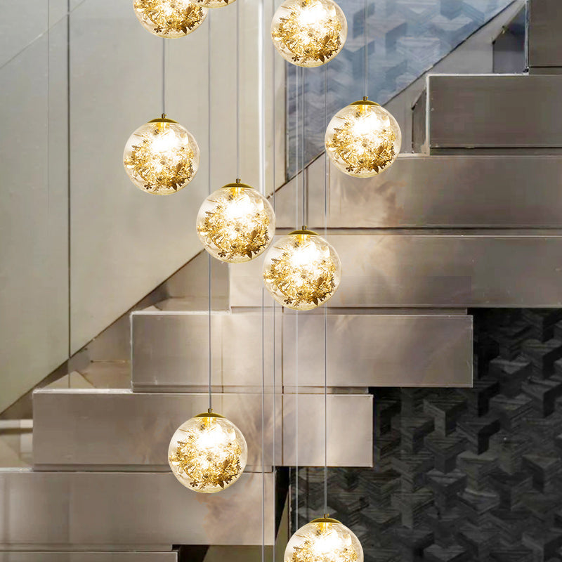 Minimalist Sphere Multi Light Chandelier Clear Glass 10-Head Stairs Pendant Lamp with Metal Flower Decor in Gold Clearhalo 'Ceiling Lights' 'Close To Ceiling Lights' 'Glass shade' 'Glass' 'Modern Pendants' 'Modern' 'Pendant Lights' 'Pendants' Lighting' 2384718