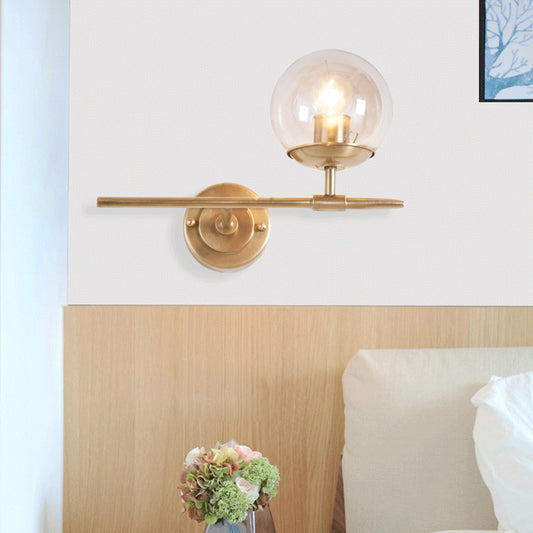 Brass Globe Wall Light Contemporary 1 Light Hand Blown Glass Sconce Light with Crossed Arm Clearhalo 'Cast Iron' 'Glass' 'Industrial' 'Modern wall lights' 'Modern' 'Tiffany' 'Traditional wall lights' 'Wall Lamps & Sconces' 'Wall Lights' Lighting' 275133